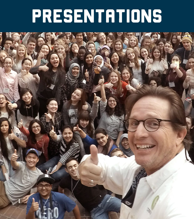 Dean Jacobs in front of large group of students all with their thumbs up.